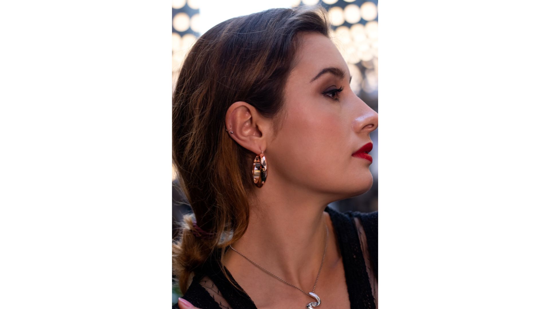 A person with red lipstick and earrings

Description automatically generated