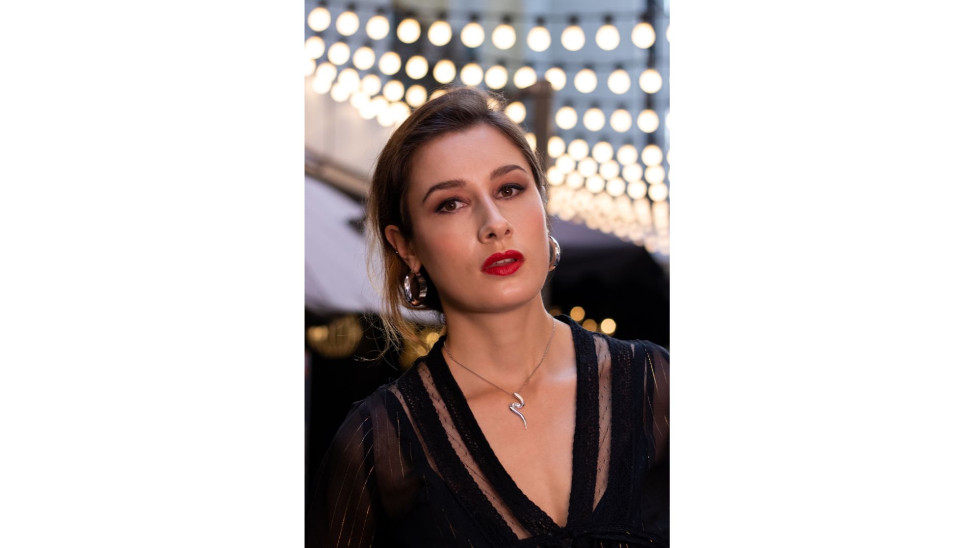 A person with red lipstick and earrings

Description automatically generated